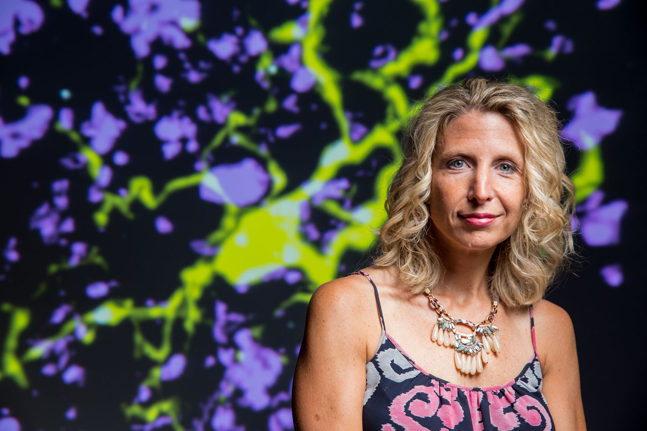 Beth Stevens in front of an image of microglia and neurons